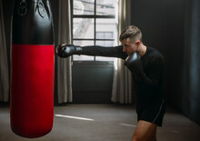 A Young Athletic Man Is Hitting A Boxing Bag. Boxer Practicing Punches In The Ring. The Athlete Strikes With A Punching Bag. 4k Video