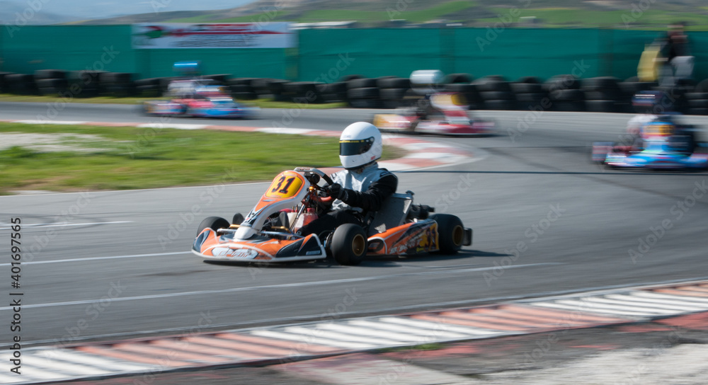 Unrecognised man driving Go-kart with speed in the on a karting track - obrazy, fototapety, plakaty 