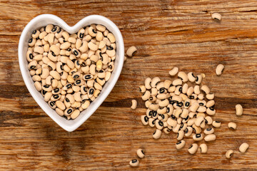 Black eye peas in a heart-shaped bowl background and texture. Top view.