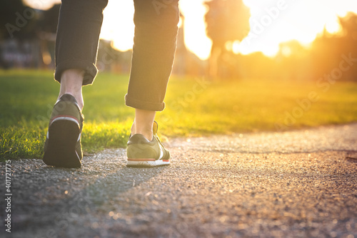 Plakat Woman walking in the park, outdoors. Closeup on shoe with rolled up jeans. Taking a step. New life concept