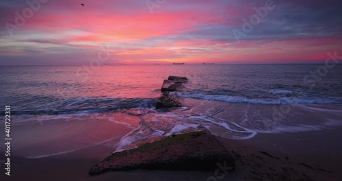 Tela Epic colorful sea sunrise with red burning sky over rocky beach, 4K dramatic vid