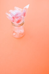 Sticker - A vertical shot of yummy candies in plastic bags in a jar isolated on a pink background