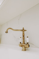 Sticker - A vertical shot of a golden faucet on a white bathroom