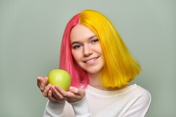 Head shot of beautiful smiling teenage girl with white smile with teeth, holding an apple