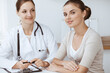 © rogerphoto - Doctor and patient are sitting and discussing health examination results in clinic office. Health care, medicine and good news concepts