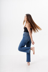 young attractive asian woman with long hair in black top, blue jeans isolated on white studio background. skinny pretty female posing on cyclorama with bare feet. model tests of beautiful lady