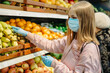 © sushytska - Young girl in medical masks makes purchases in a supermarket in search of food.