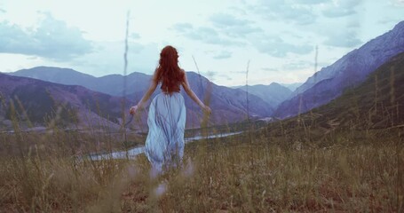 Wall Mural - Carefree girl with red hair raising her hands up to the wind, embracing freedom and tranquility, enjoying scenic view of mountains 4k footage