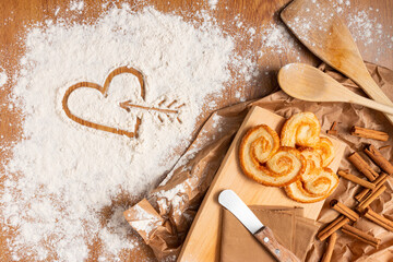 Poster - A yummy composition for St. Valentine's day - palmier cookies, a heart on flour, cinnamon sticks, and kitchen utensils