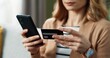 © VAKSMANV - Caucasian young beautiful joyful satisfied female shopper tapping on cellphone, making purchase on internet on smartphone paying with credit card sitting in cozy home. Close up online shopping concept