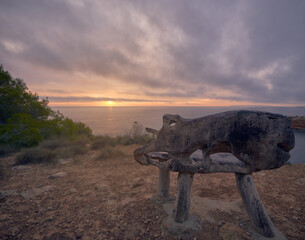 An exotic wooden bench overlooking the ocean captured in Ibiza at sunset