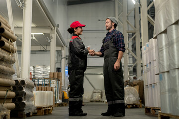 Poster - Young professional in overalls and checkered shirt shaking hand of colleague