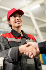 Poster - Young smiling female engineer in workwear looking at colleague during handshake