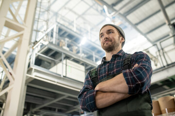 Poster - Young confident male worker of large factory standing with crossed arms