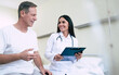 © My Ocean studio - Happy cute confident woman doctor with a tablet in hands talks with the patient in the hospital ward
