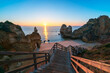 Wooden staircase above a deserted beach with sun rising on the horizon over the sea with clear skies
