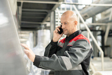 Aufkleber - Bald mature worker with smartphone by ear pressing button on control panel