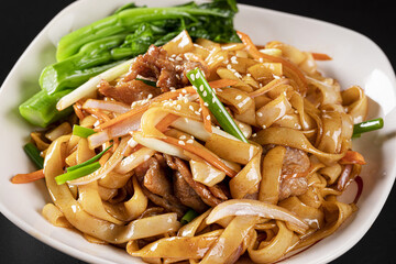 A closeup shot of a plate of pasta with meat and vegetables