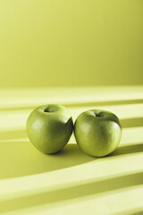 Poster - A vertical shot of fresh green apples with shadow from window isolated on green background