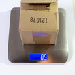 The product in a cardboard box being weighted on a postal weight scale
