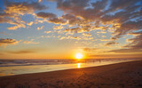 Fototapeta Mapy - Colorful ocean beach sunset with deep blue sky and sun rays