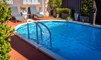 Above ground pool sunken below ground and surrounded by decking.