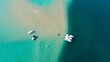 Aerial view of boats anchored on a sand bar in crystal clear blue water.