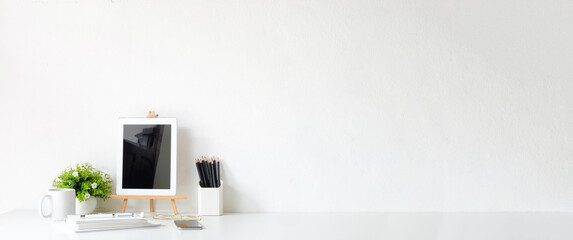 Minimal workplace with mock up digital tablet, pot plant, smart phone on white table. Copy space for product display montage. 