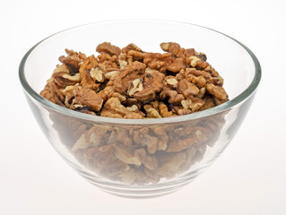 Peeled walnut kernels in a glass bowl on a light background. Close-up image