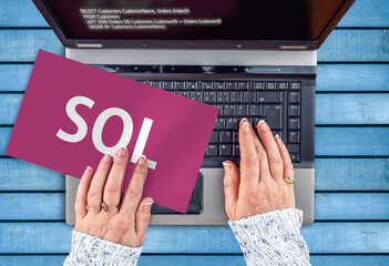 Poster - SQL programming language. Paper width word SQL and hands on laptop keyboard
