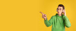 © master1305 - Choosing. Caucasian young man's portrait on yellow studio background. Beautiful male model in green outfit with cellphone. Concept of human emotions, facial expression, sales, ad, beauty. Flyer.