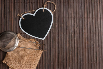 Poster - A top view of a wooden surface with a heart decoration and a tea strainer with copy space