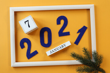 Calendar for January 7 :blue numbers 2021 in a gray frame, a cube with the number 7 and the name of the month on a yellow background with a spruce branch