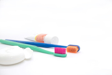 a small tube of toothpaste, white dental floss and two colored toothbrushes with bright bristles for