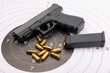 © Atlantist studio - Automatic handgun pistol and bullets on bull eye target background