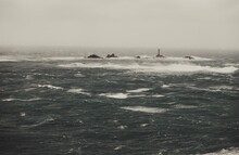 Longships Lighthouse Amidst Stormy Rough Seas And Breaking Atlantic Ocean Waves Over Rocks At Lands End Cornwall, UK After Storm Bella Gale Force Winds Surge Through The Coastline.