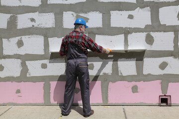 Wall Mural - Worker control styrofoam, polystyrene insulation of wall, using level tool, home renovation