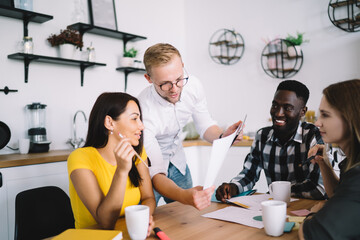 Wall Mural - Concentrated young colleagues working with papers at table in kitchen