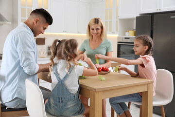 Canvas Print - Happy family cooking together at table in modern kitchen