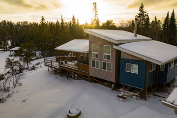a newly built cabin / cabana under a fresh snowfall in northern canada. golden hour, sunsetting behi