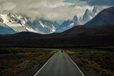 Fototapeta Na sufit - Asphalted road with the peaks of a rocky and snowy mountain on the horizon. Fitz Roy mountain in Argentina Horizontal Photograph