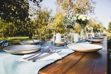 Wooden served table on a background of green nature. Vase with flowers.