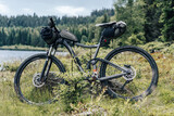 Fototapeta Na ścianę - Mountain bike packed with lots of bags for bikepacking. Bike with equipment for long distance travel, adventure or expedition. Bikepacking next to lake.