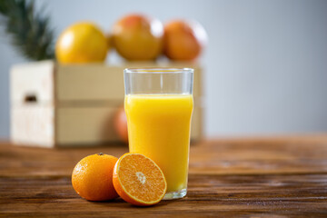 Dewy glass of orange juice standing on wooden table. Transparent cup full of sweet beverage with fruit cut in half next to. Fresh healthy liquid.