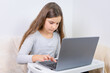 © QKon Studio - Portrait of attractive cute focused girl 6-7 old sitting using laptop indoor white background distance learning