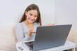 © QKon Studio - Portrait of attractive cute happy smiling girl 6-7 old sitting using laptop indoor white background distance learning