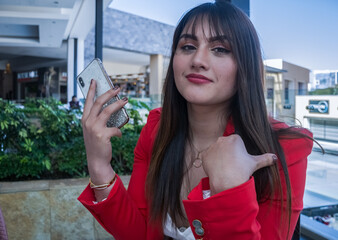 close up of pretty young woman with a cellphone in in the hand. Dressed with red jacket