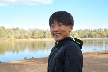 Wall Mural - Portrait of young sporty Asian boy by the Lake. Teenager concept