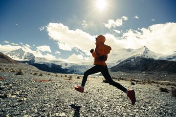 Woman trail runner cross country running in high altitude winter nature