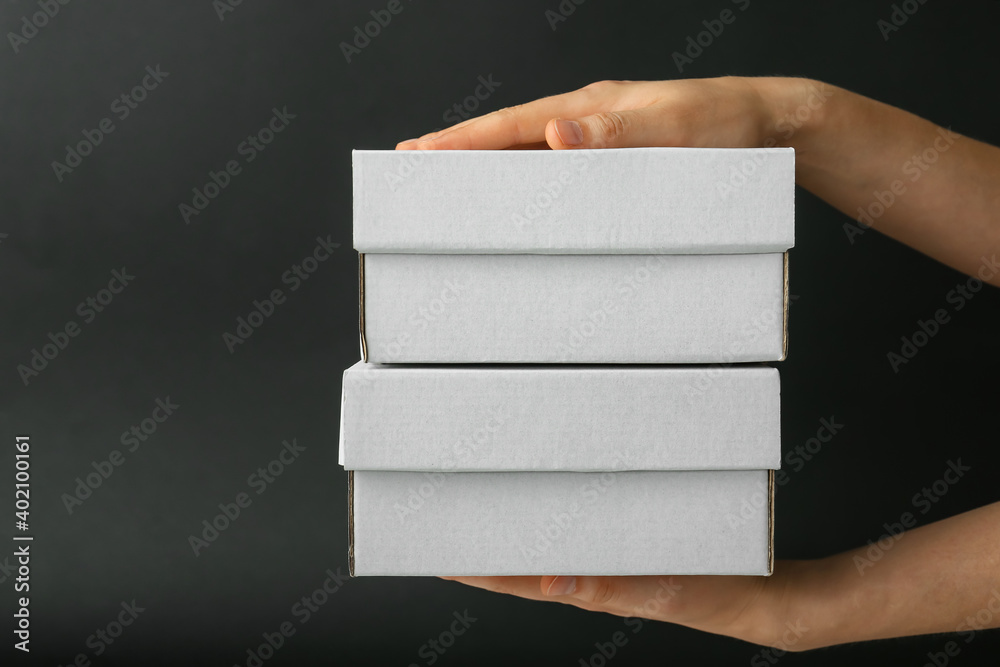 Hands with blank cardboard box on dark background
